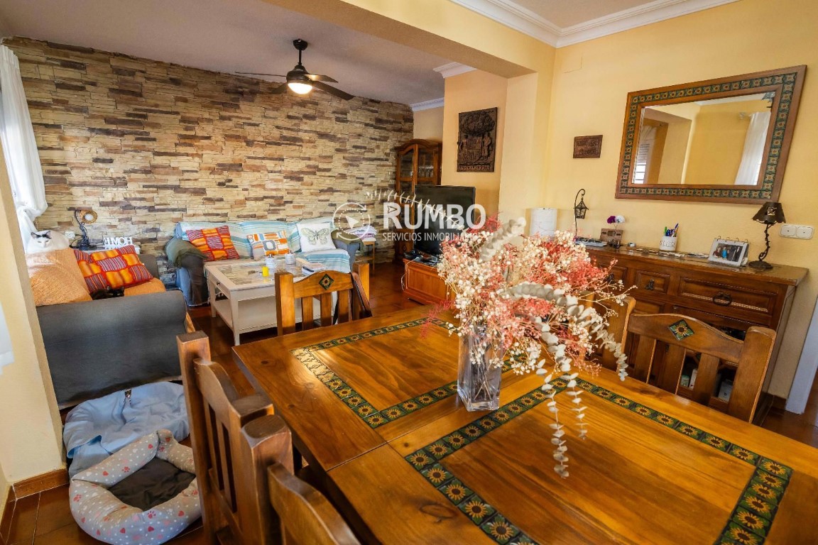 nterior de sala con mesa de madera, sofá y pared decorativa de piedra