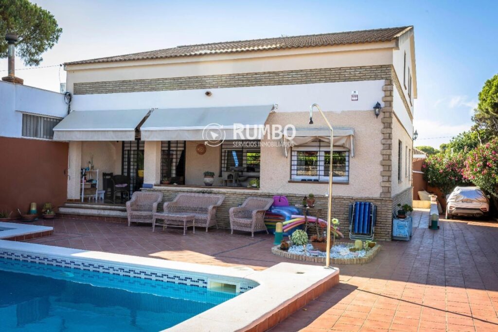 atio trasero con piscina, zona de estar y porche con toldos blancos